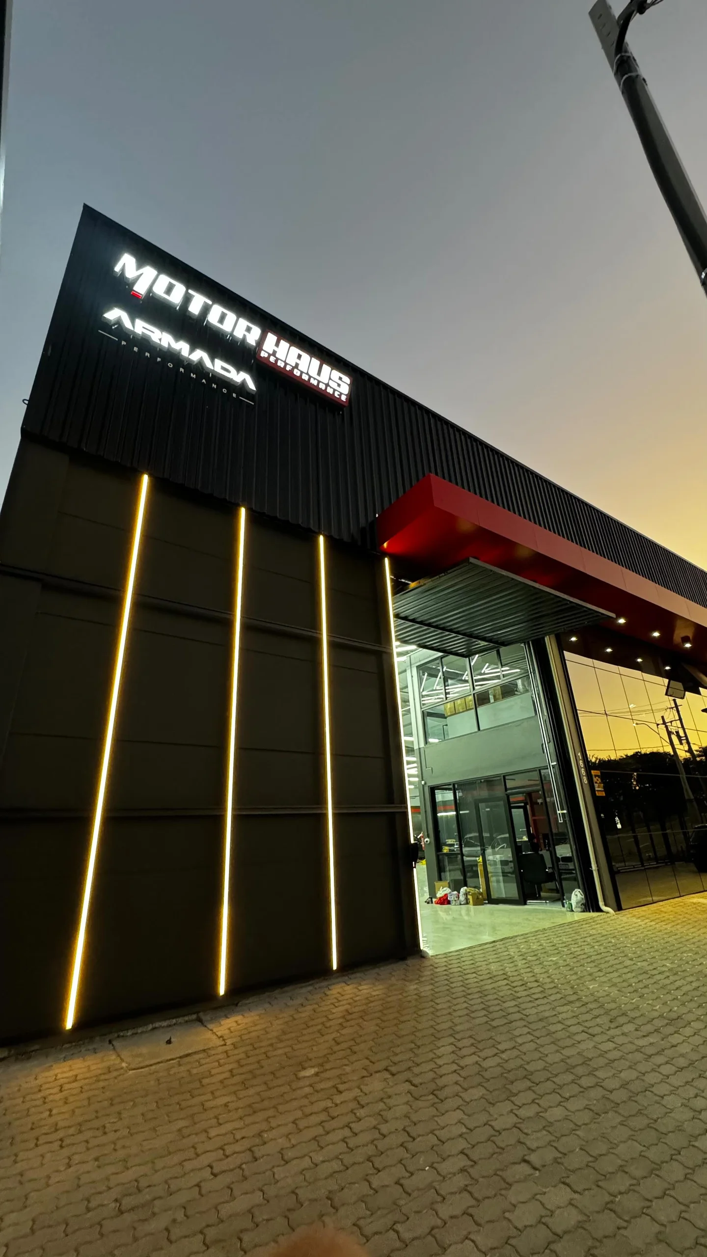 Fachada da MotorHaus ao entardecer, com letreiro da marca e entrada da oficina.
